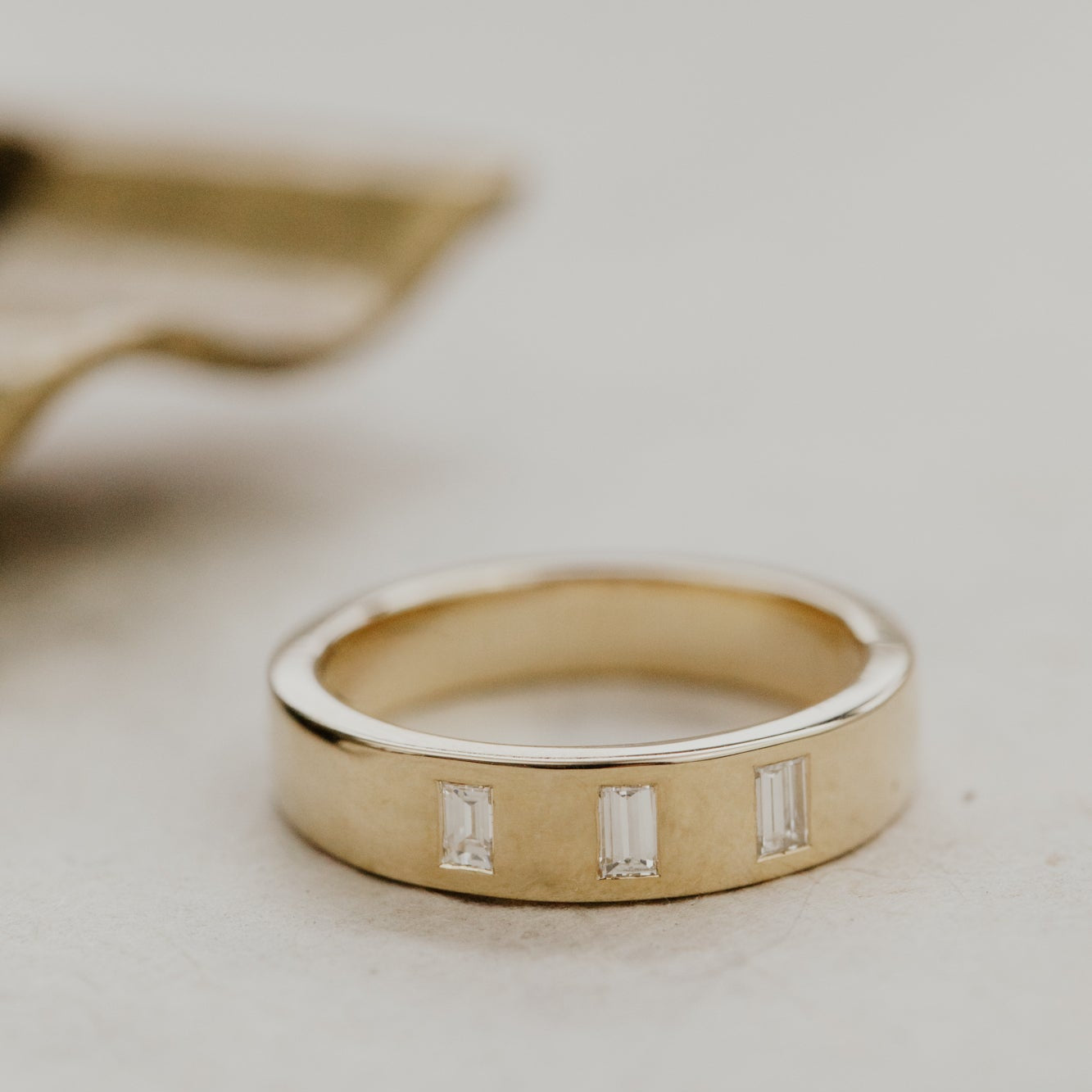 The Jaden gold wedding band with three small diamonds on a light background.
