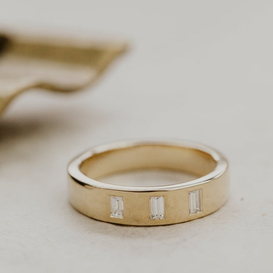 The Jaden gold wedding band with three small diamonds on a light background.