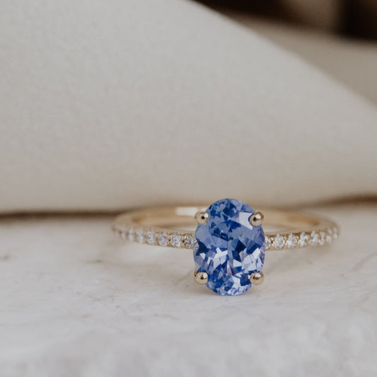 The Jenna Engagement Ring with a blue Sri Lanka sapphire gemstone and a pave diamond band on a neutral background.