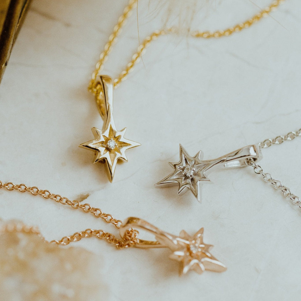 Star-shaped gold necklaces on a soft fabric background