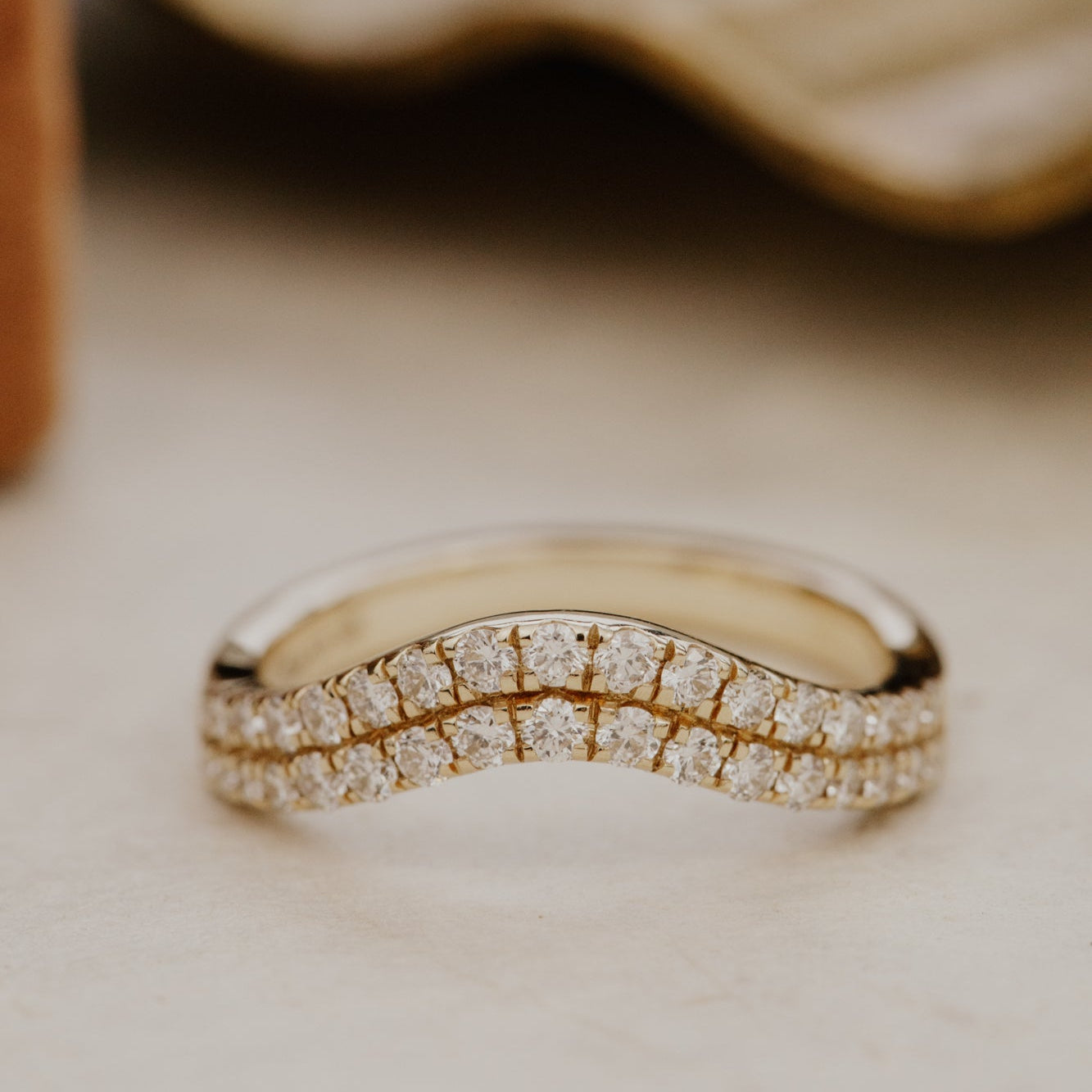 Gold Rose diamond tracer wedding band on a textured surface.