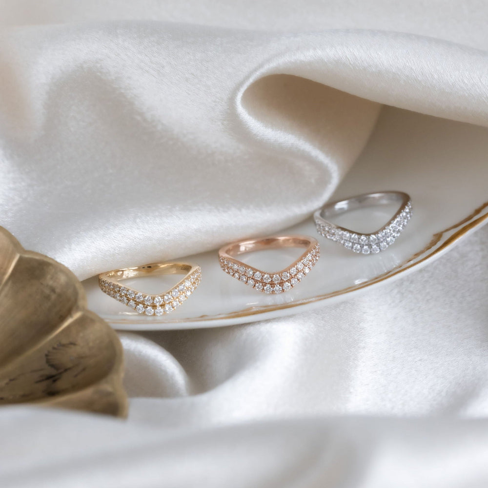 Three Rose diamond tracer bands in yellow, rose, and white gold on a white fabric background.