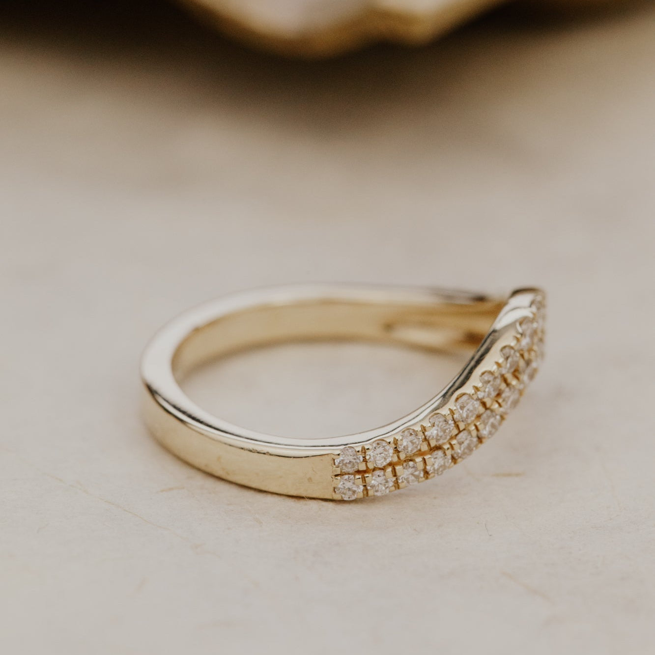 Gold Rose diamond tracer wedding band on a beige background.