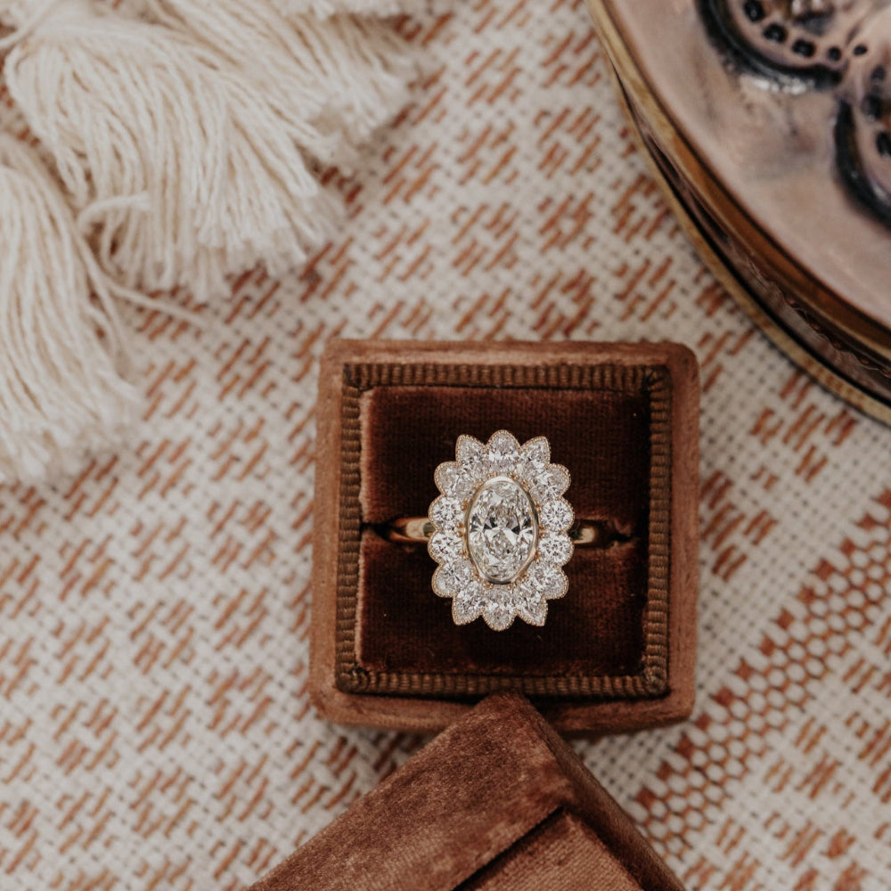 Diamond ring in a brown velvet box on a textured fabric background