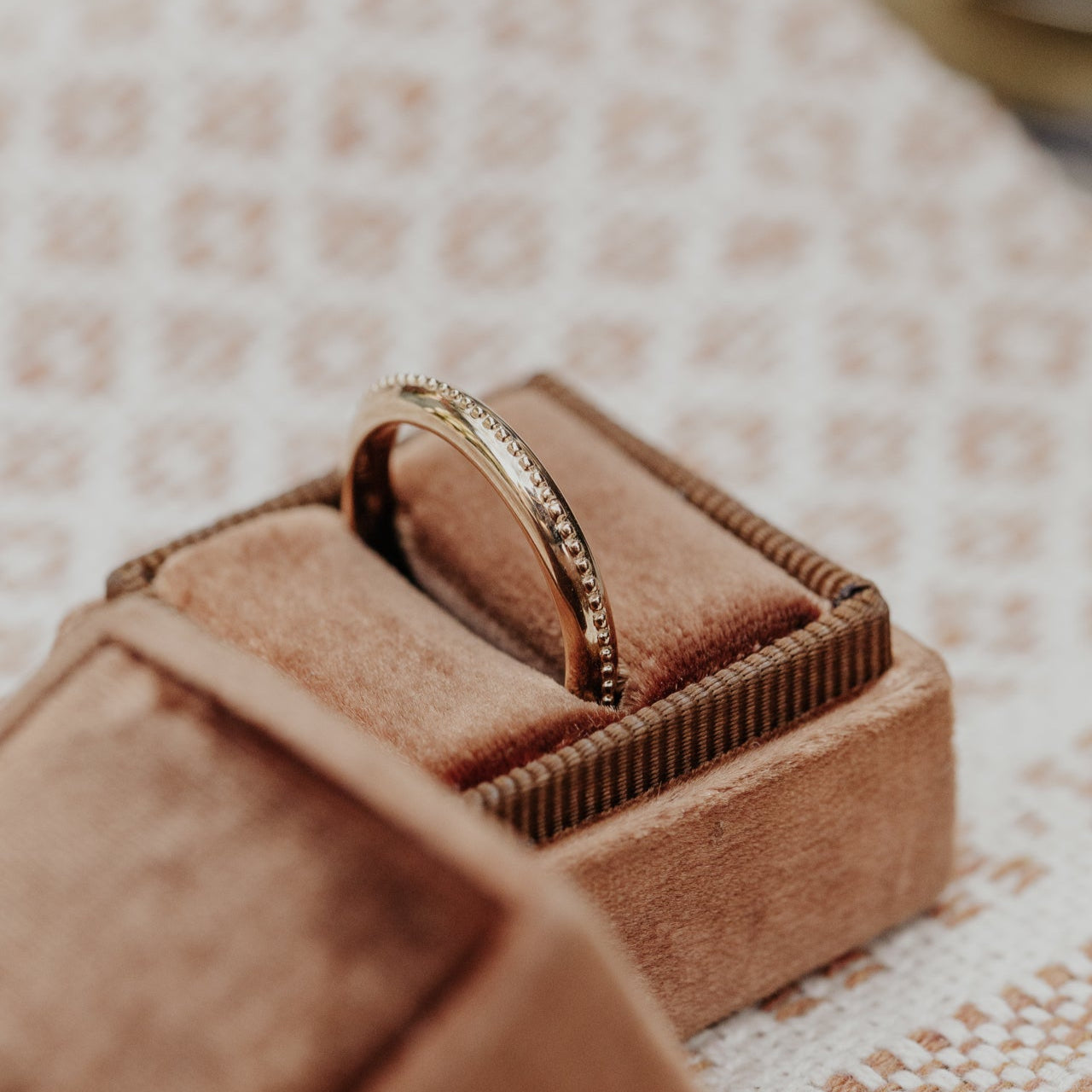 Gold ring in a brown velvet box on a textured surface