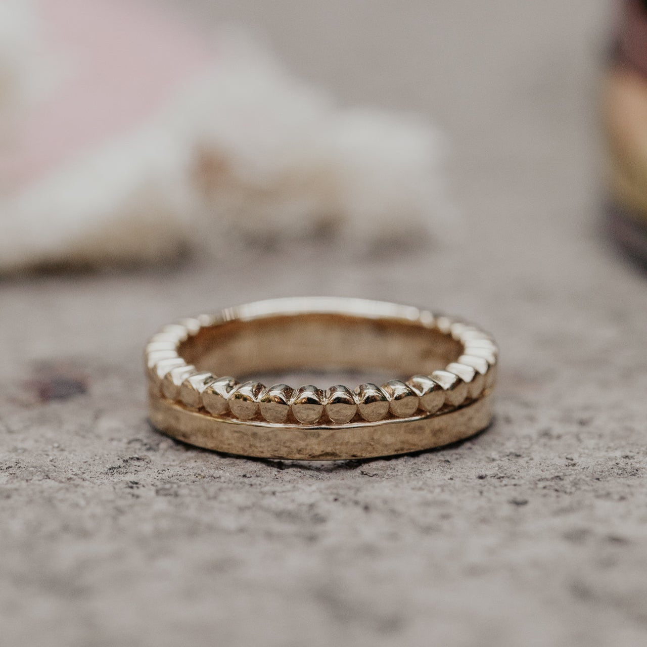 Gold bands stacked on a textured surface with a blurred background