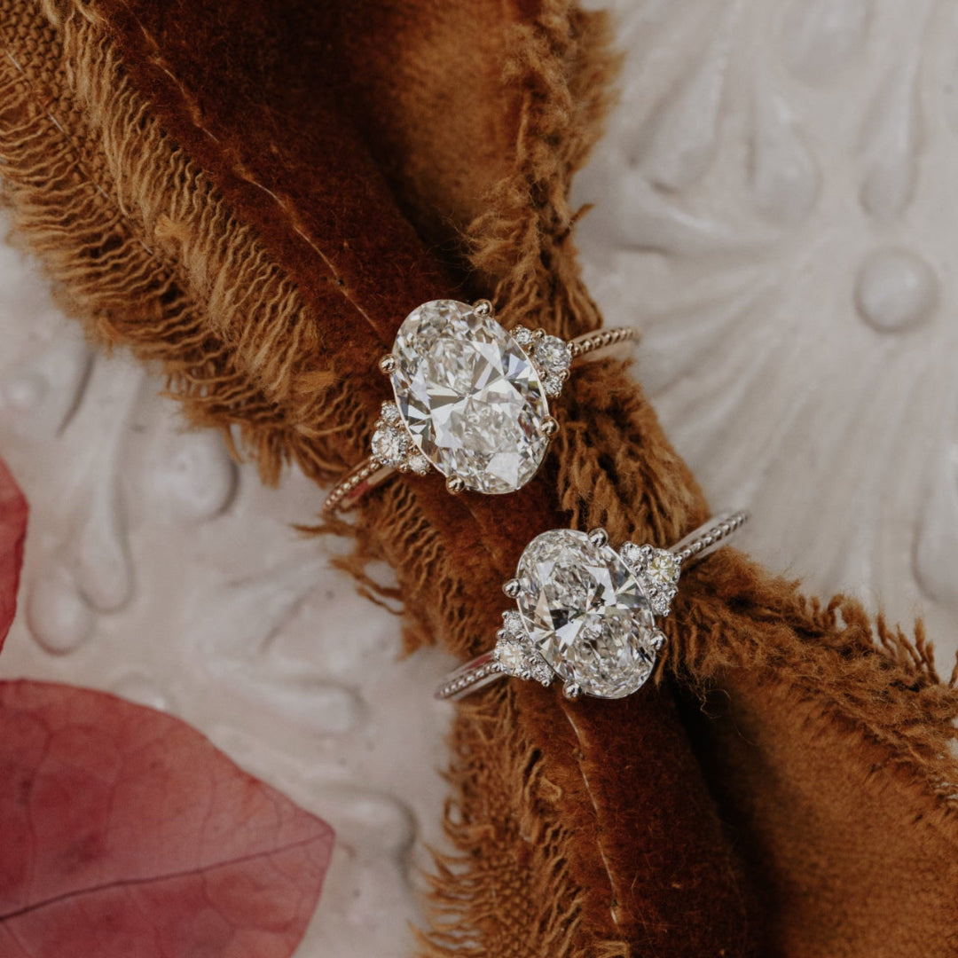 Two diamond rings on a textured surface with a brown fabric background