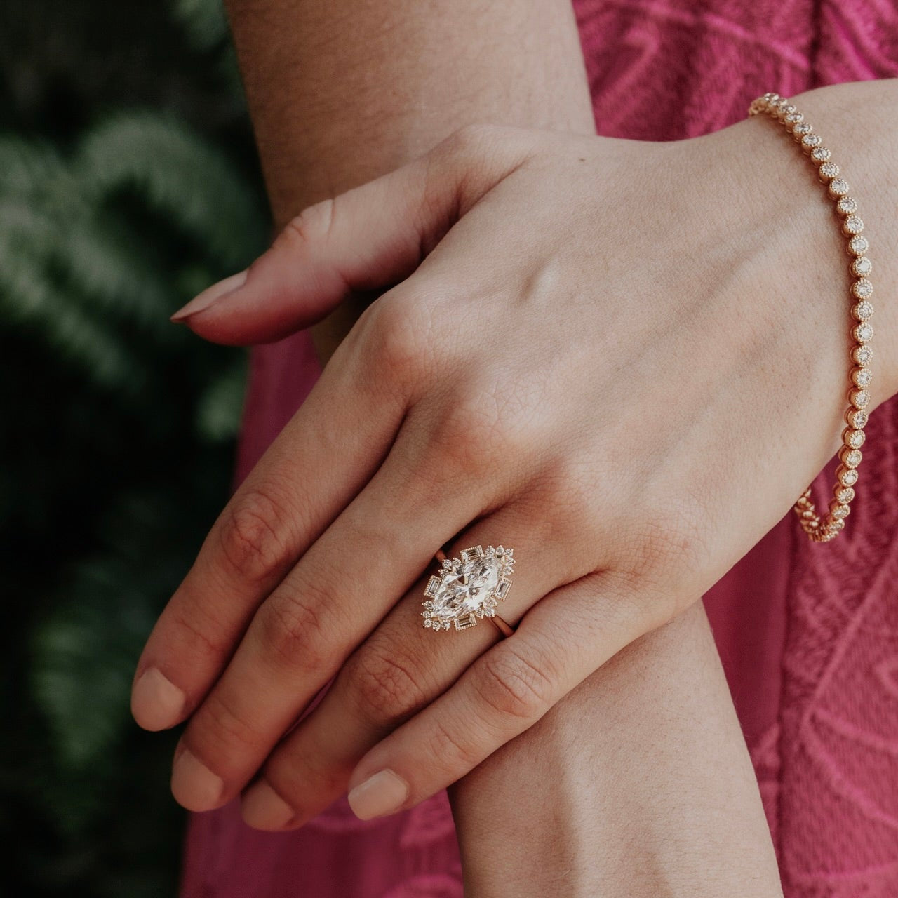 Close-up of a hand wearing a marquise diamond halo ring with a blurred background
