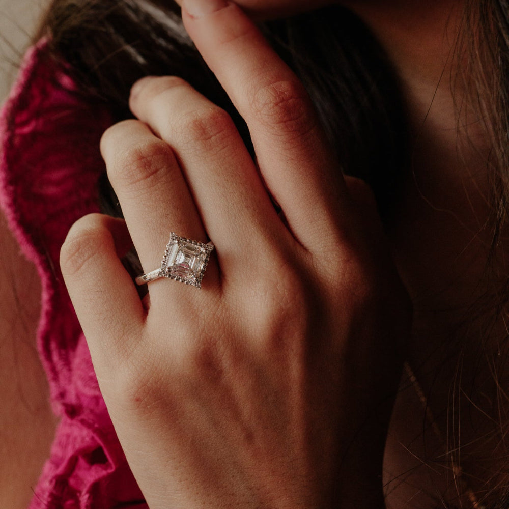 Close-up of a hand wearing a asscher diamond ring with a blurred background