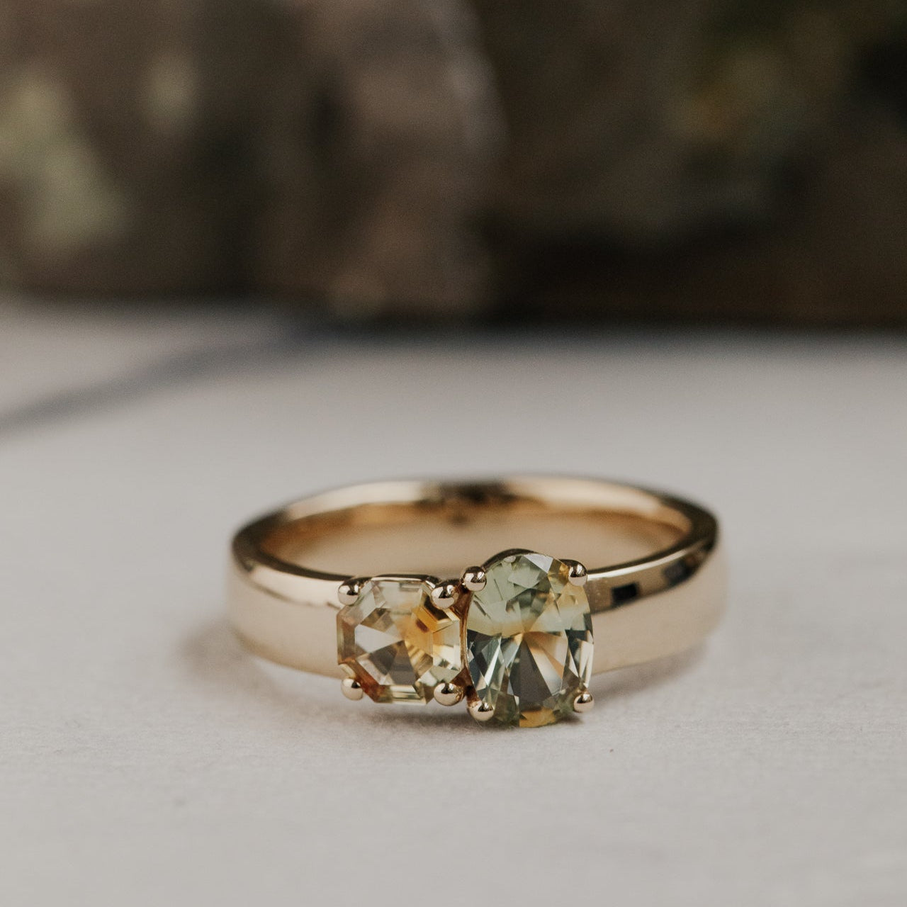 Gold ring with green Montana sapphire gemstones on a neutral background
