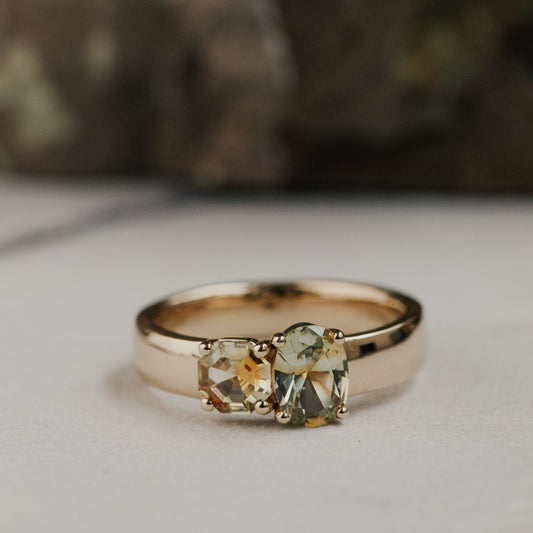 Gold ring with green Montana sapphire gemstones on a neutral background