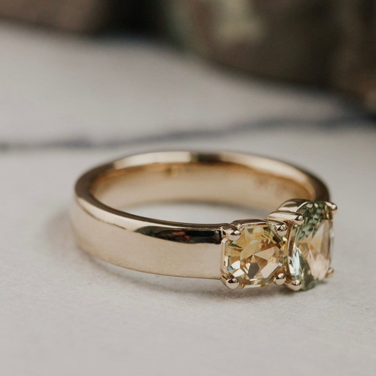 Gold ring with two green Montana sapphire gemstones on a light background