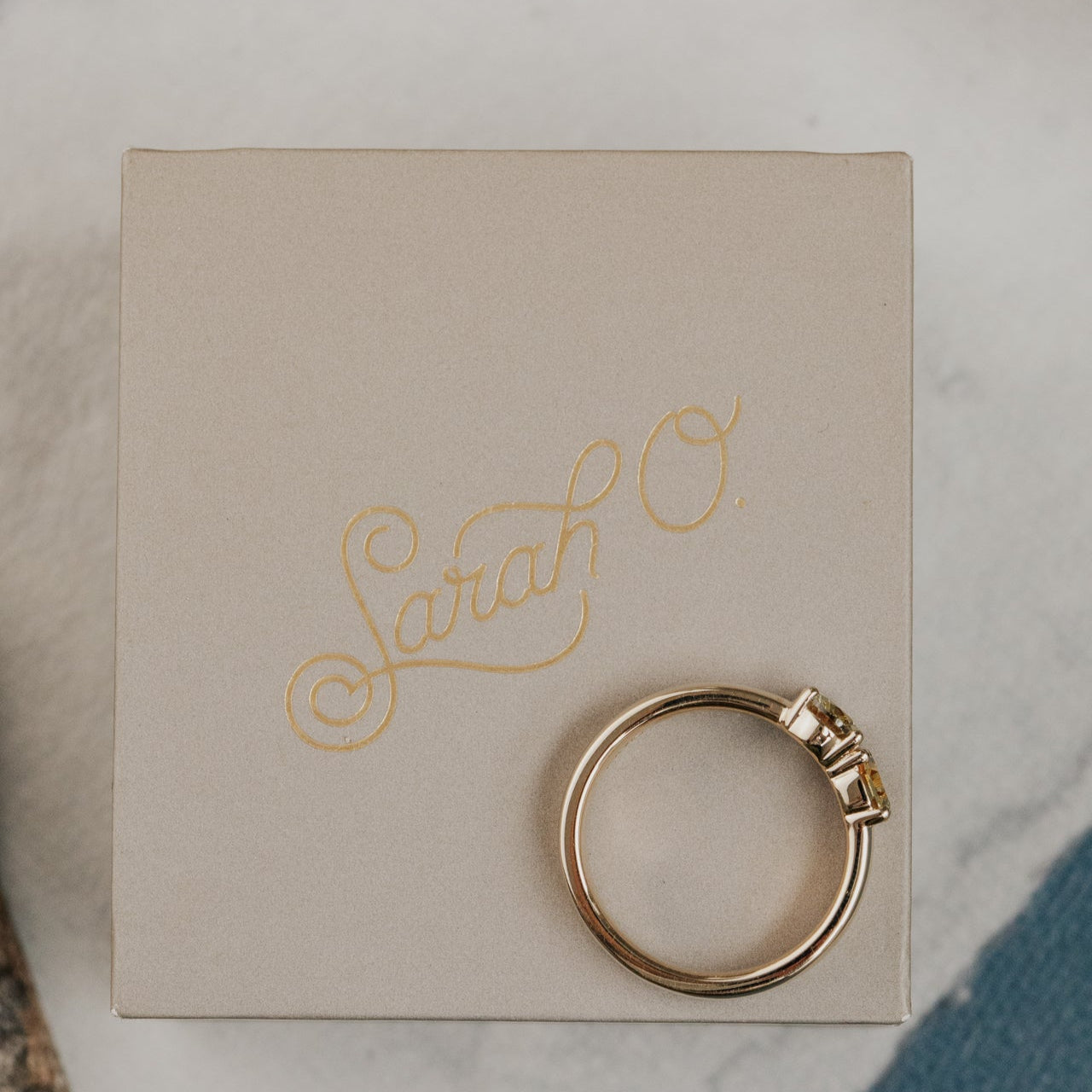 Gold Montana sapphire ring on a box with 'Sarah O.' branding on a marble surface