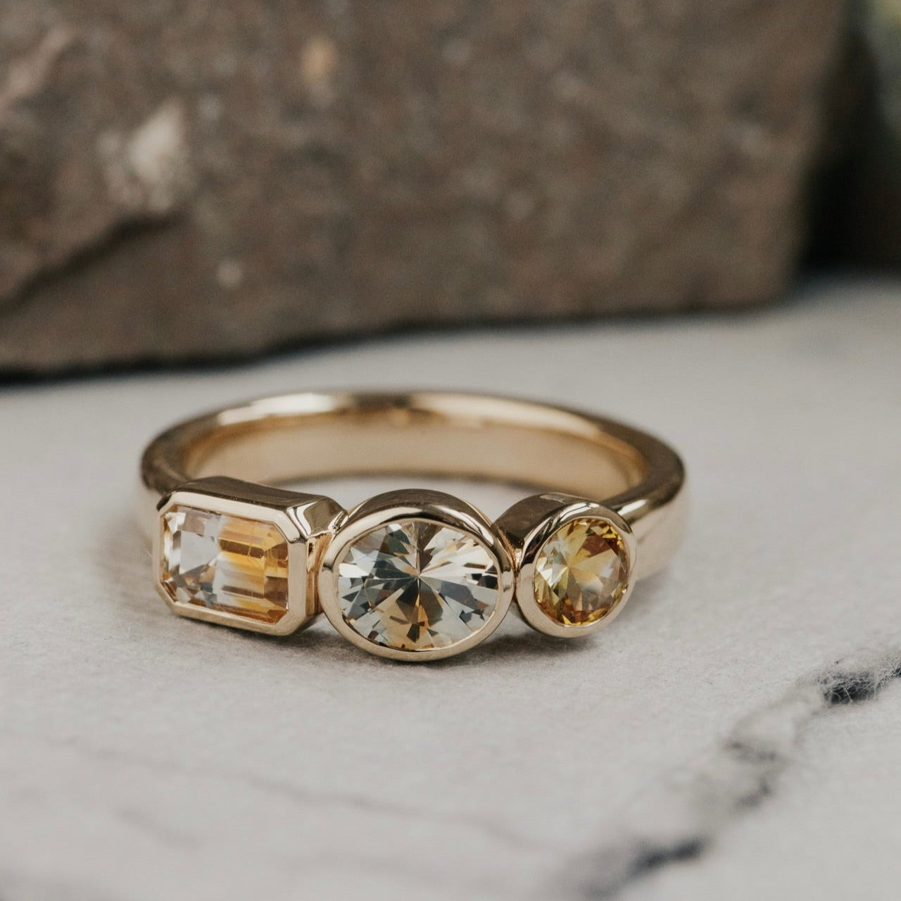 Gold ring with three Montana sapphire gemstones on a marble surface