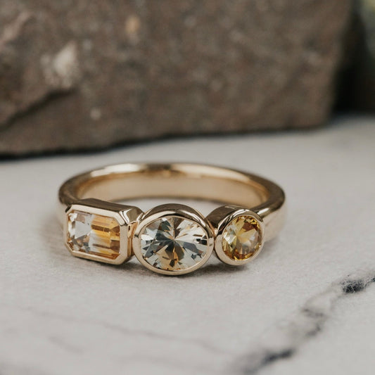 Gold ring with three Montana sapphire gemstones on a marble surface