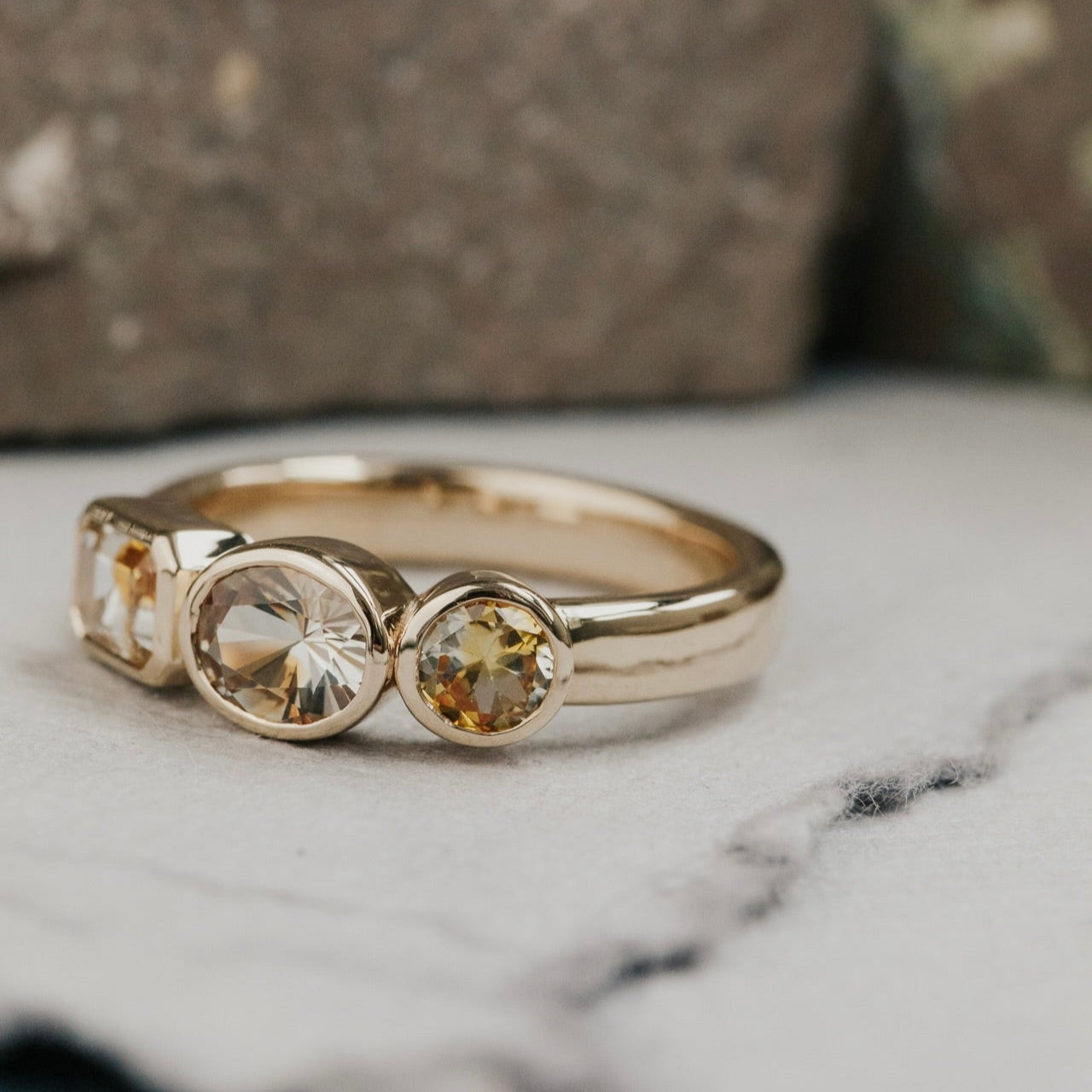 Gold ring with three Montana sapphire gemstones on a marble surface