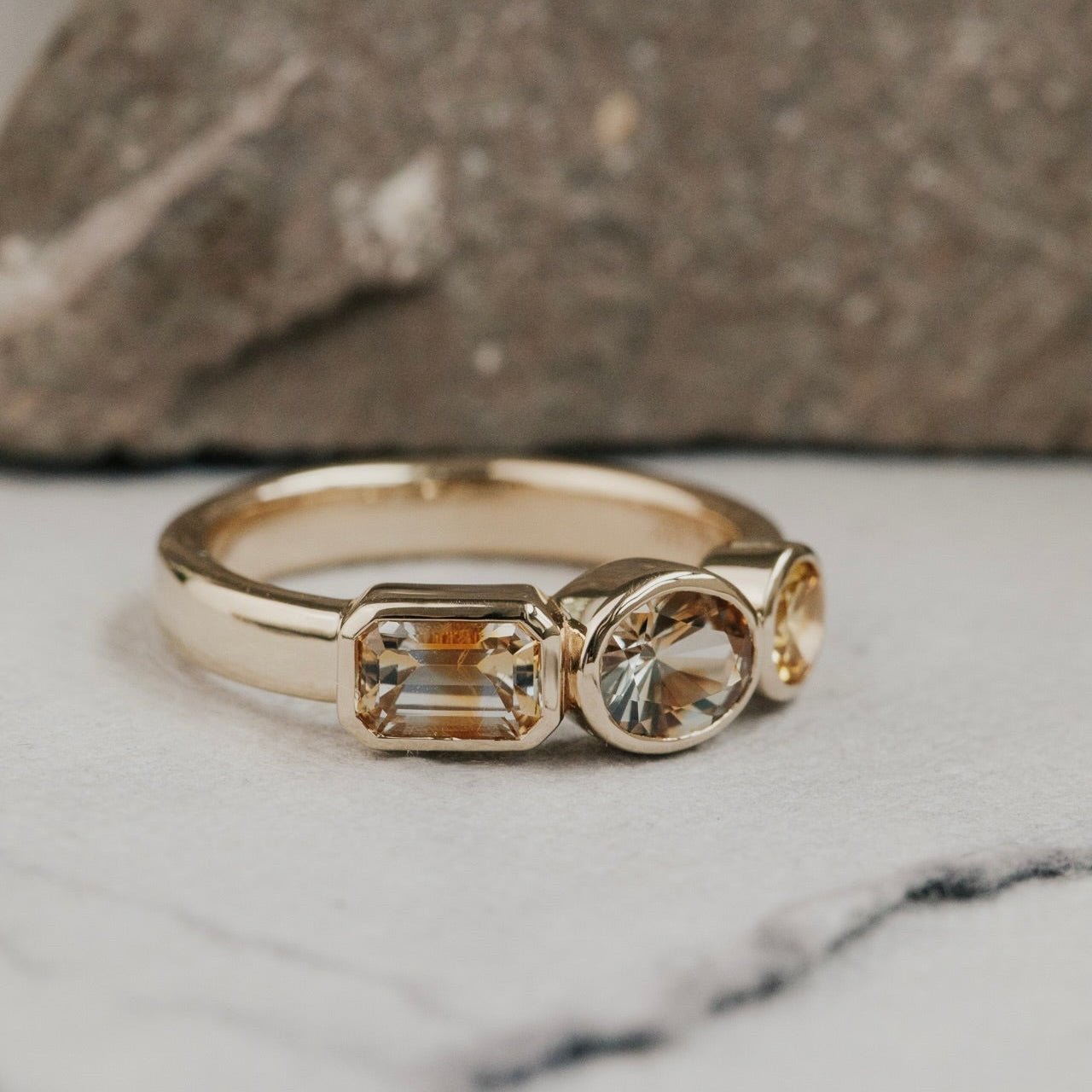 Gold ring with Montana sapphire gemstones on a marble surface