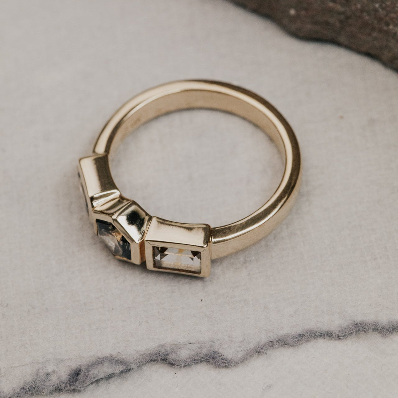 Gold ring with  Montana sapphire gemstones on a marble surface