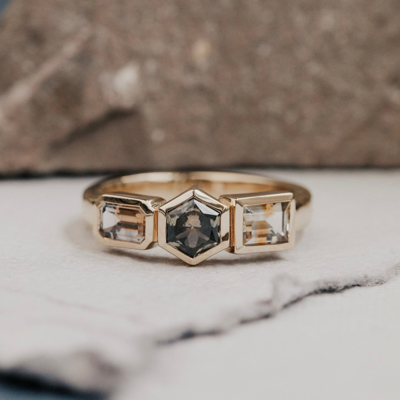 Gold ring with three Montana sapphire gemstones on a marble surface