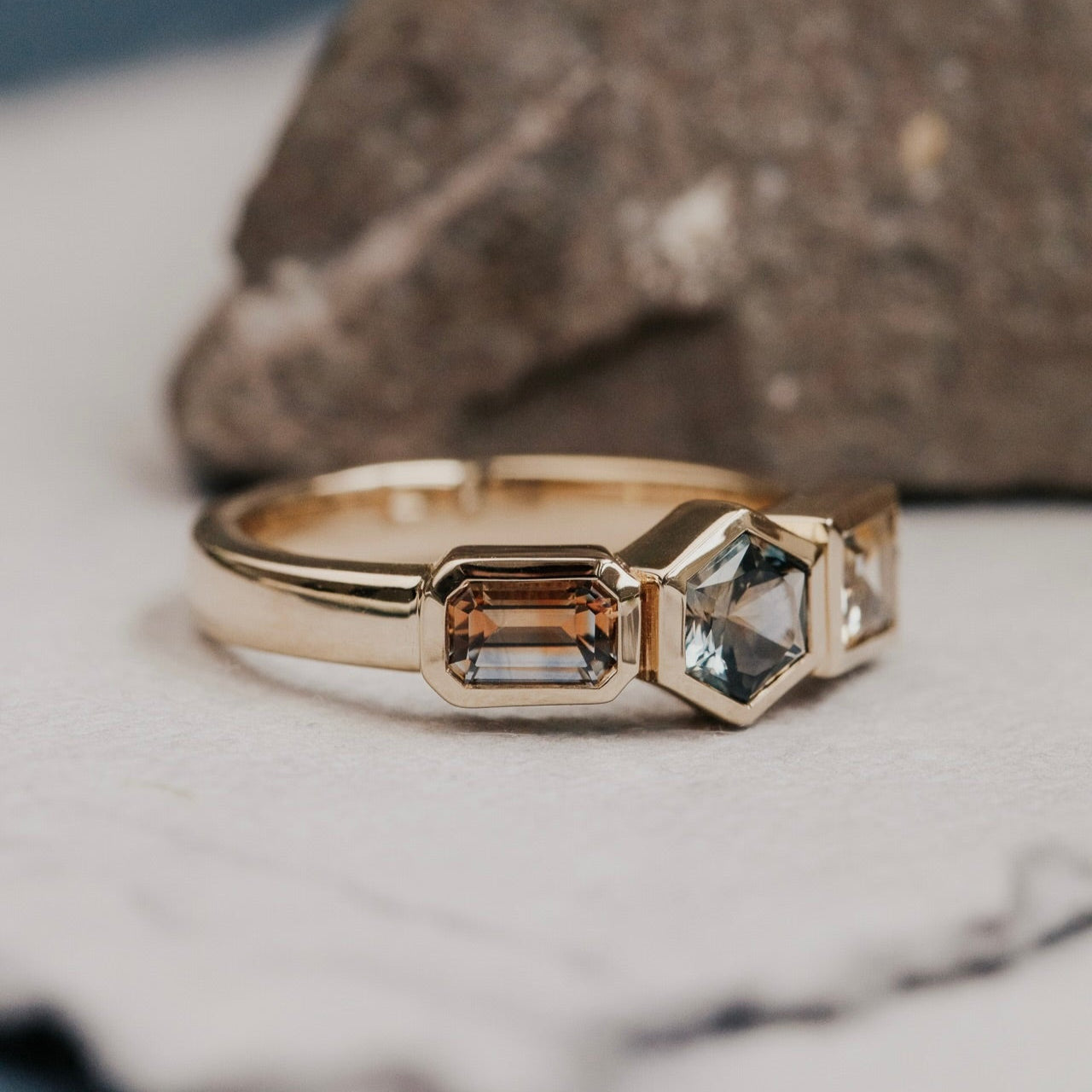 Gold ring with two rectangular Montana sapphire  gemstones on a marble surface