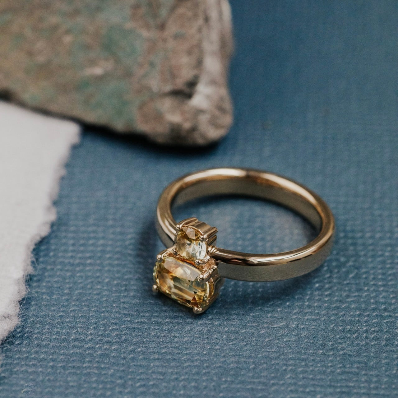 Gold ring with a Montana sapphire on a textured blue surface