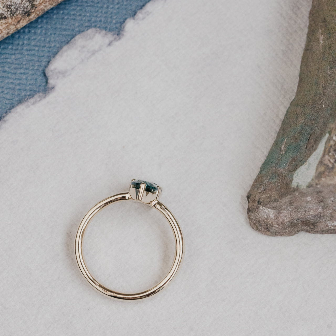 Gold ring with a blue Montana sapphire gemstone on a textured surface