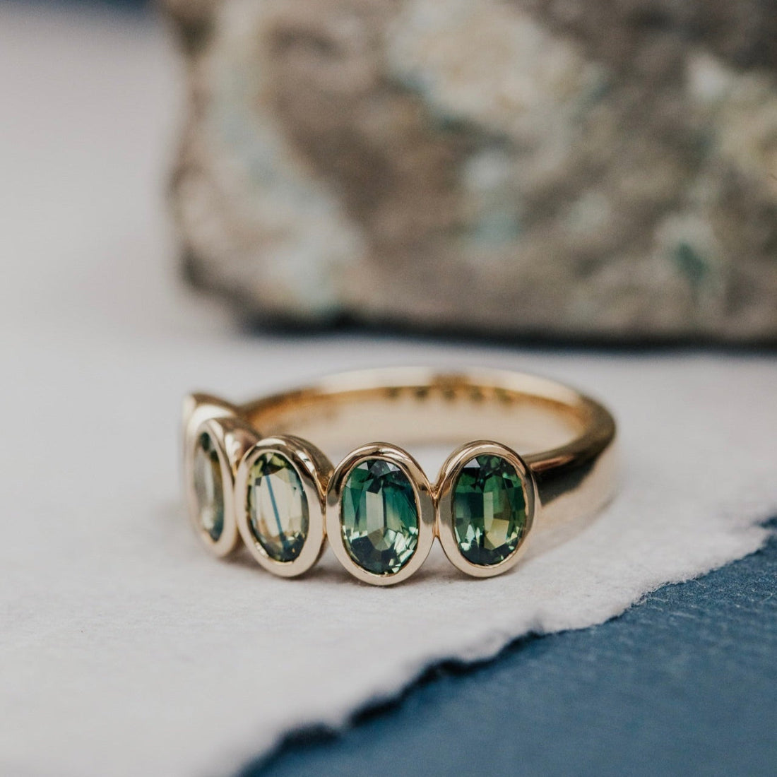Gold ring with green Australian Sapphire gemstones on a textured surface
