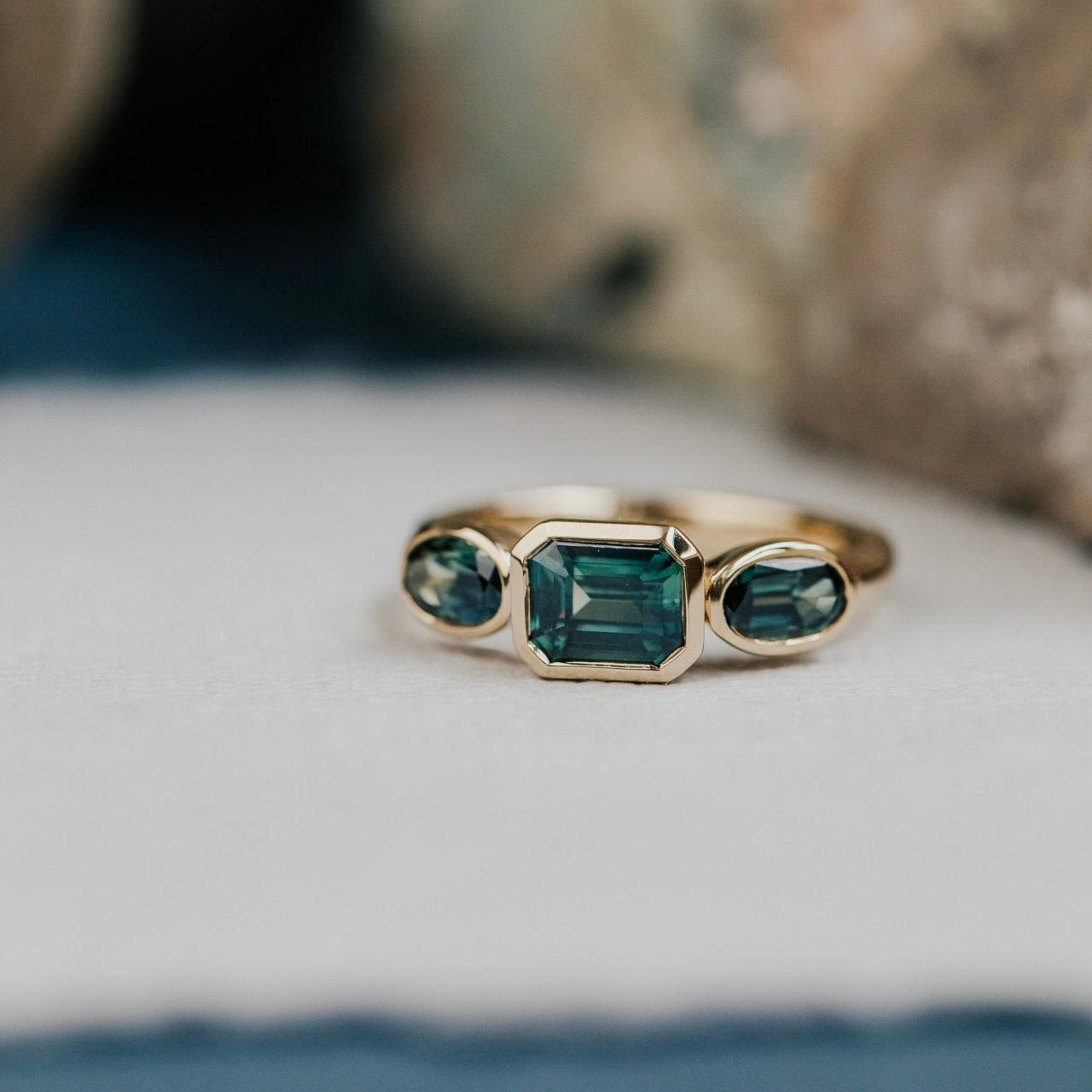 Gold ring with green Australian sapphire gemstones on a textured surface