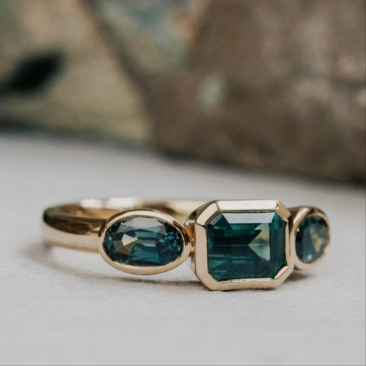 Gold ring with green Australian sapphire  gemstones on a neutral background