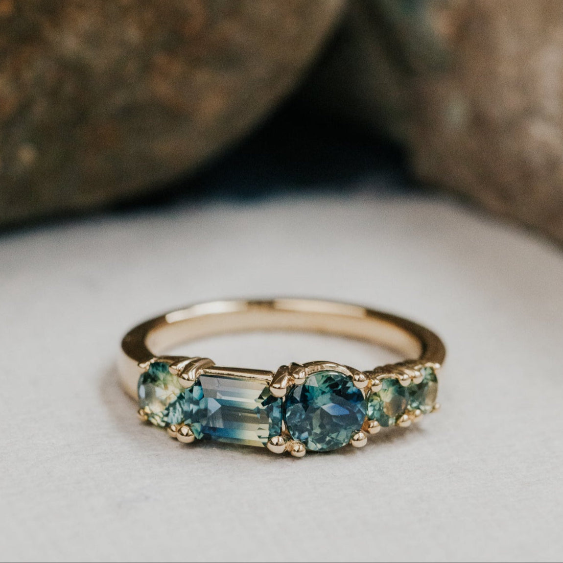 Gold ring with blue Australian sapphire gemstones on a neutral background