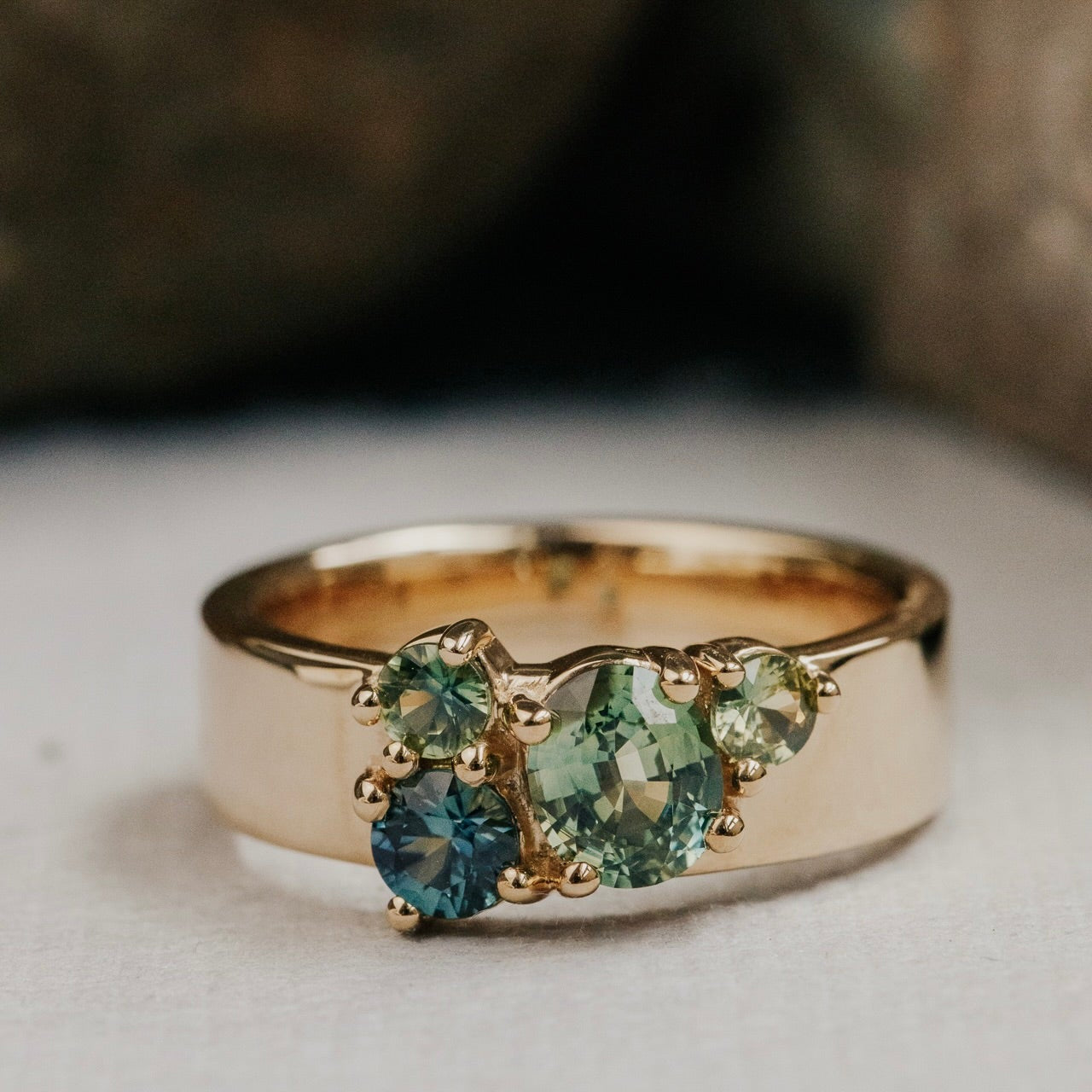 Gold ring with green Australian Sapphire gemstones on a neutral background