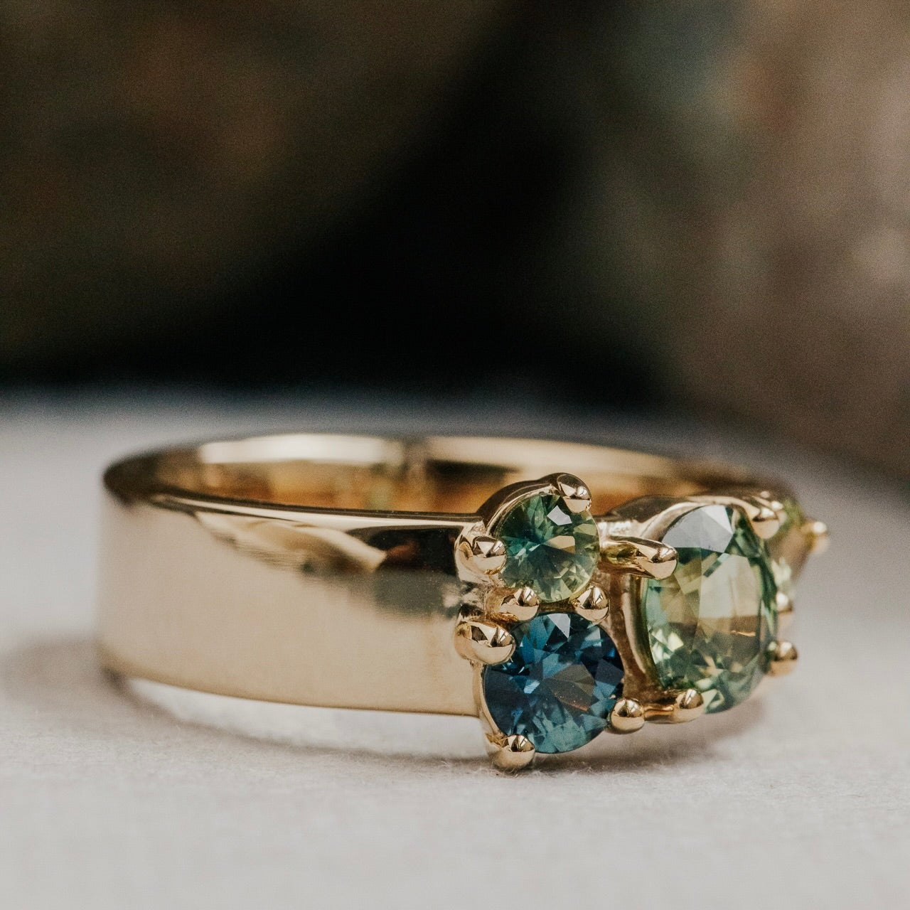 Gold ring with green Australian Sapphire gemstones on a neutral background