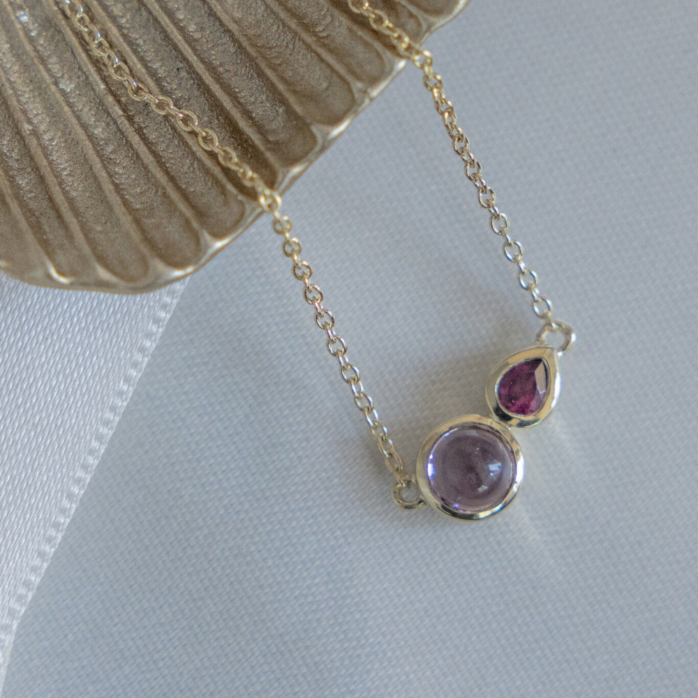 Necklace with purple and pink gemstones on a light background