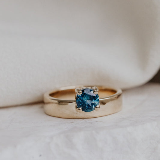 Gold Sezanne ring with a blue Montana sapphire on a soft white background.
