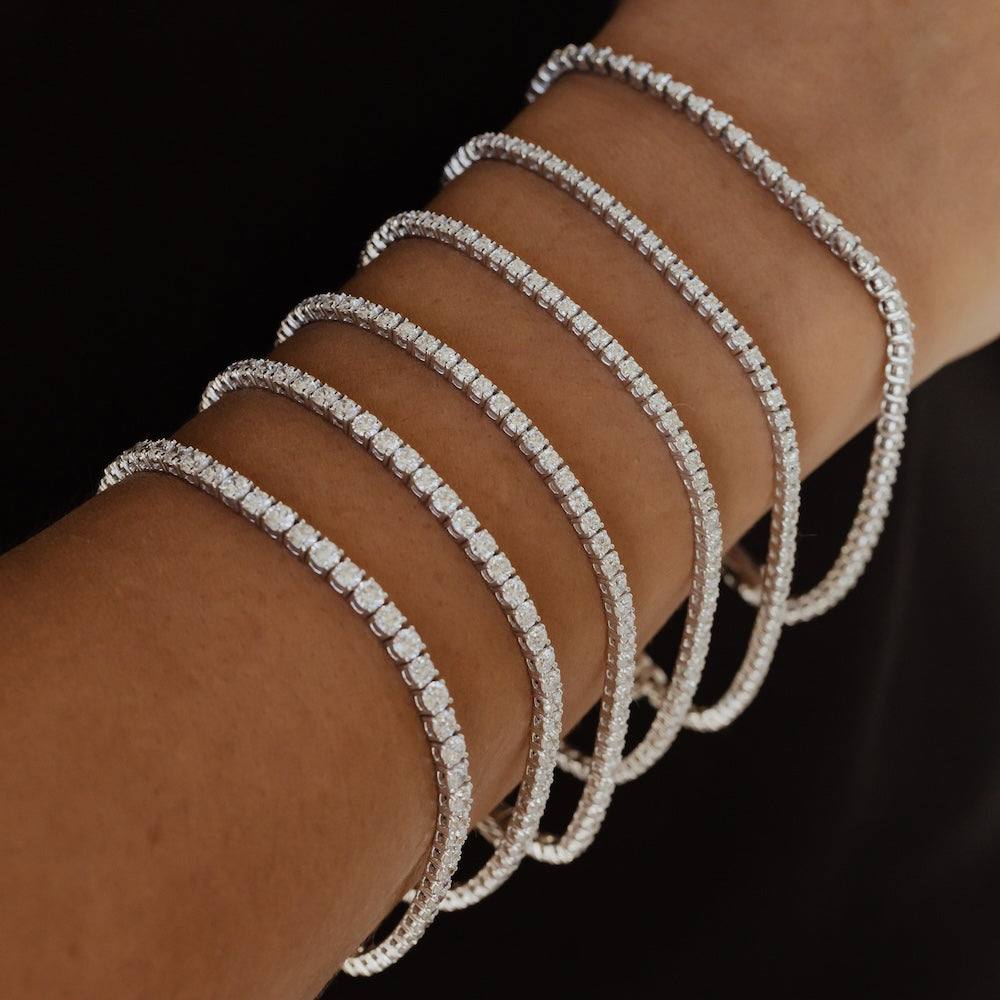 Close up of a person wearing multiple Signature diamond tennis bracelets in different sizes. 