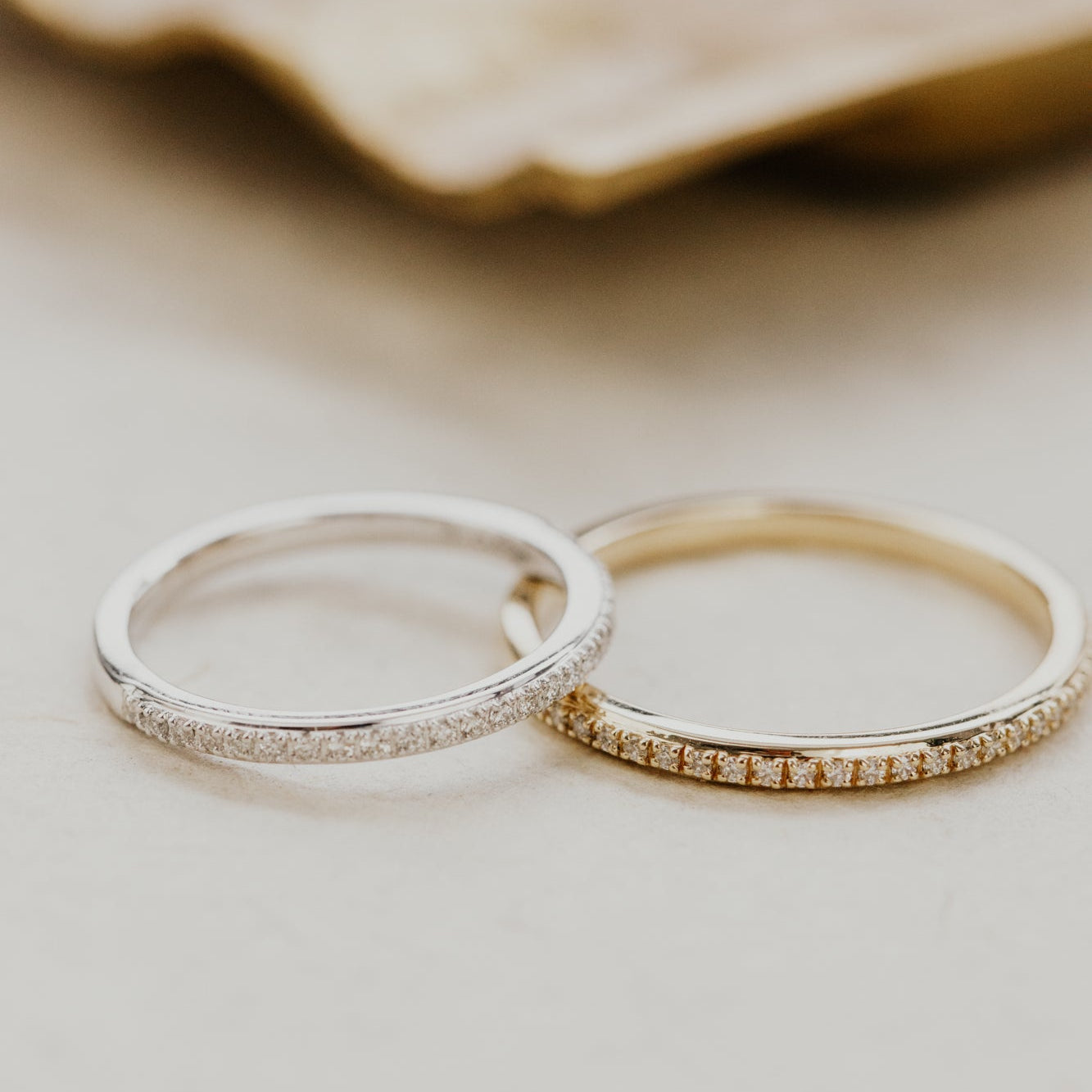 Two single row diamond wedding bands in yellow and white gold on a neutral background.