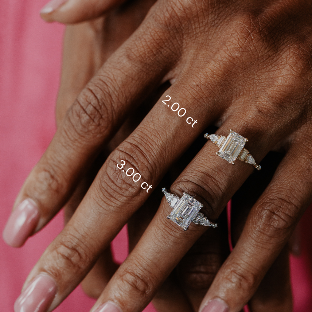 Two diamond emerald cut rings on fingers with size labels against a pink background