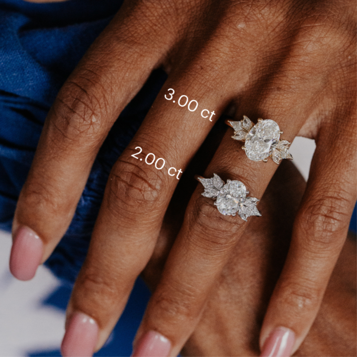 Two oval diamond rings on a hand with measurements indicated.