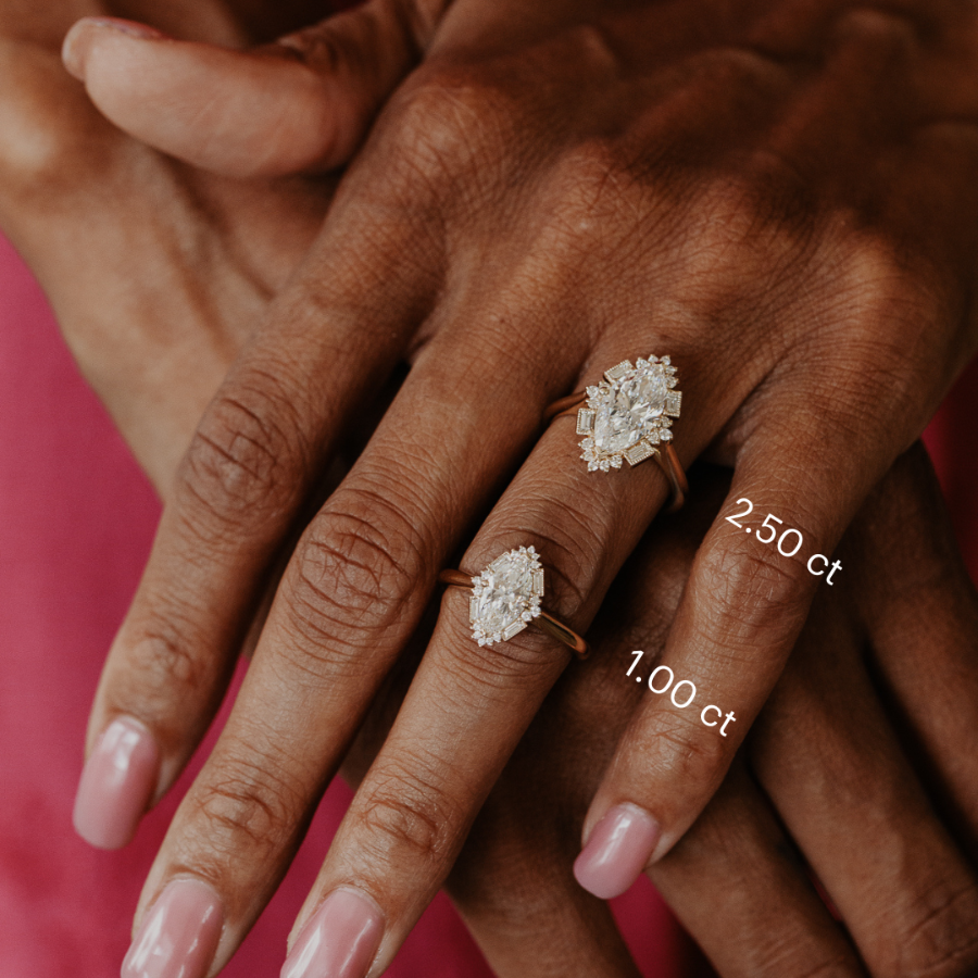 Close-up of a hand wearing two marquise diamond rings with visible carat weight labels.