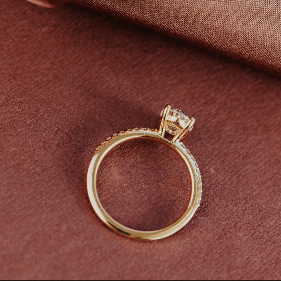 Yellow gold engagement ring with a diamond on a brown fabric background