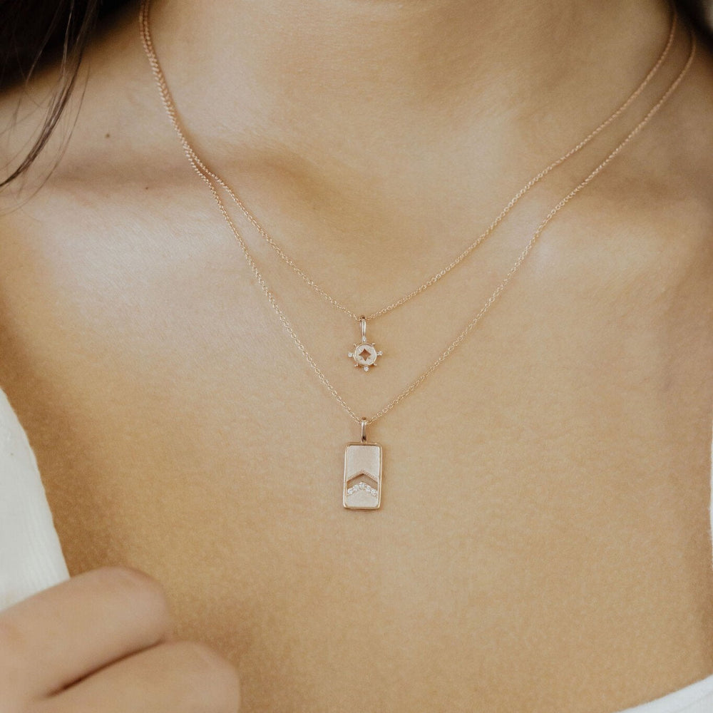 Gold necklace with a charm worn on a persons neck