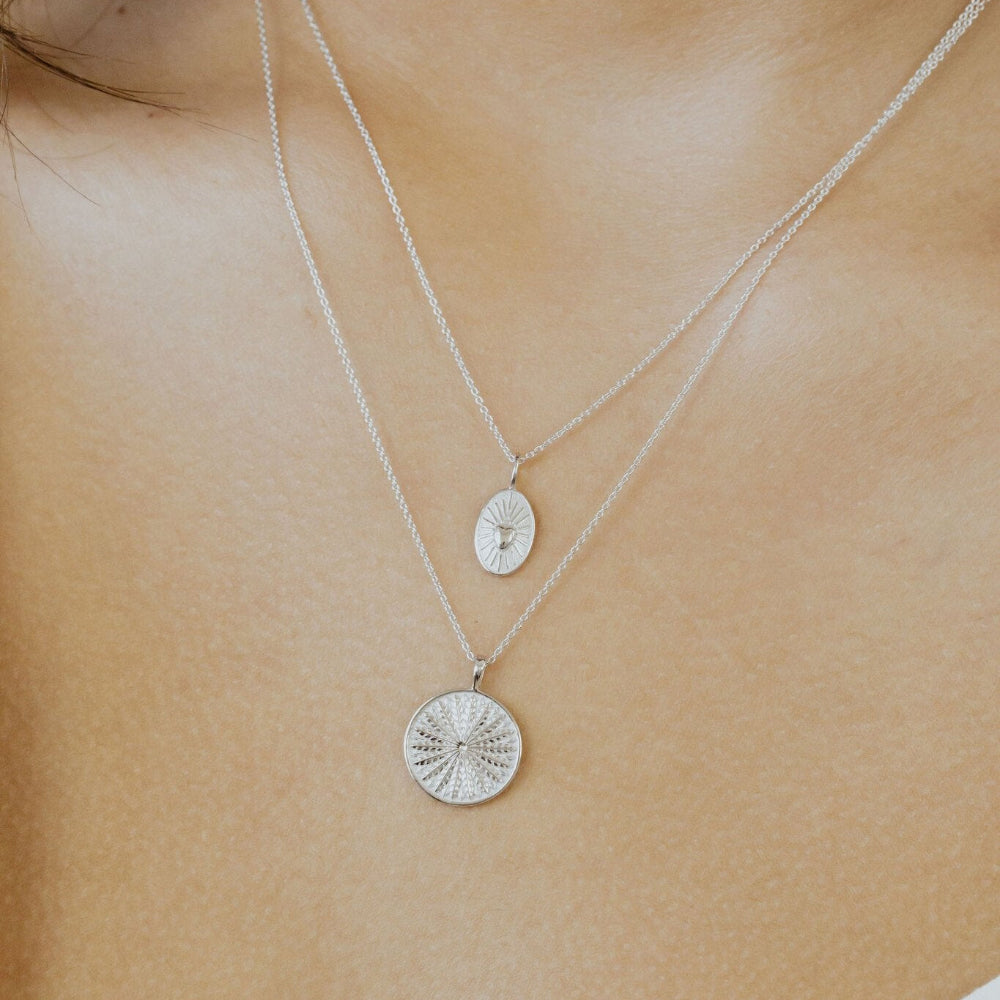 Close-up of a white gold necklace with a pendant on a person's neck 