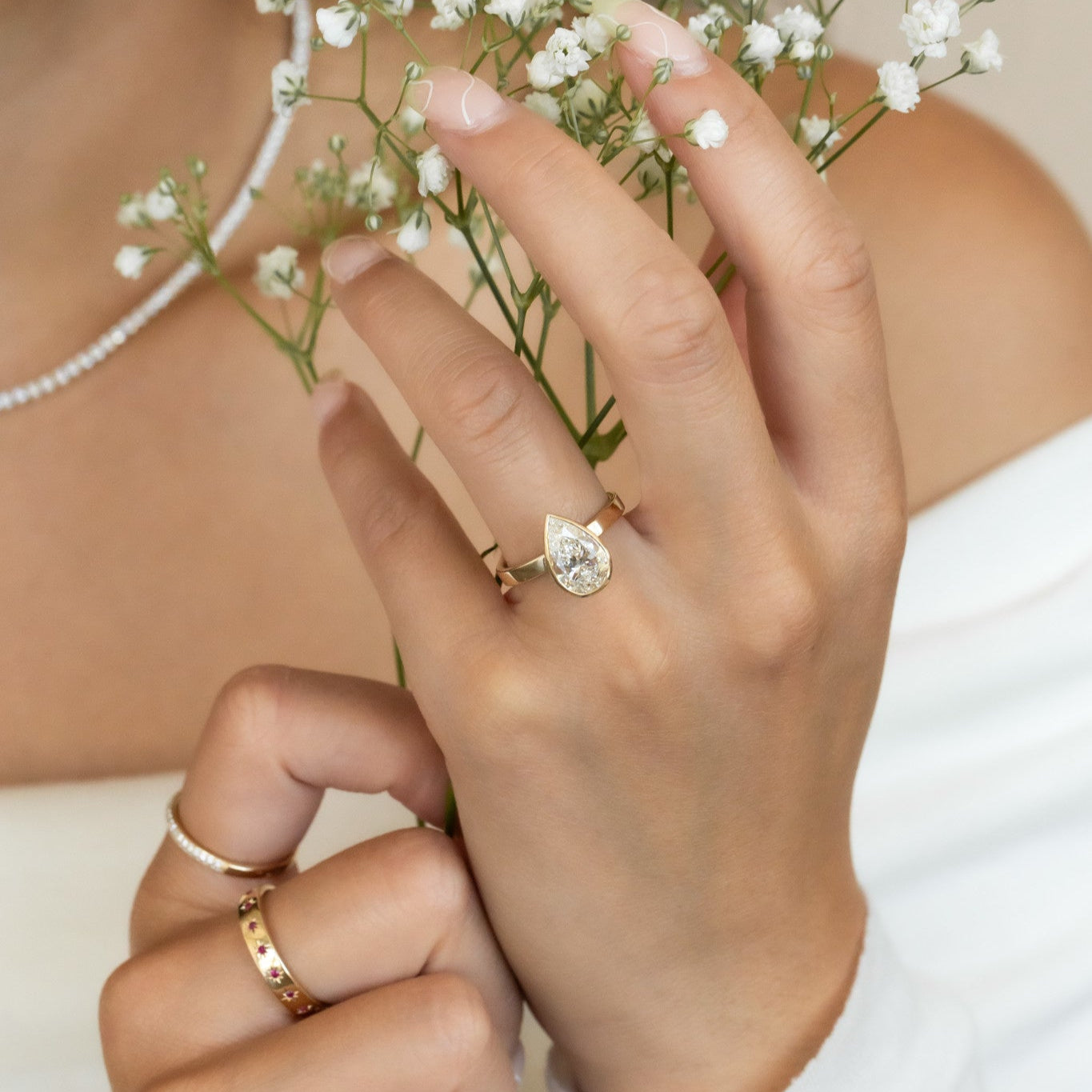 The Elena pear solitaire engagement ring on a models hand