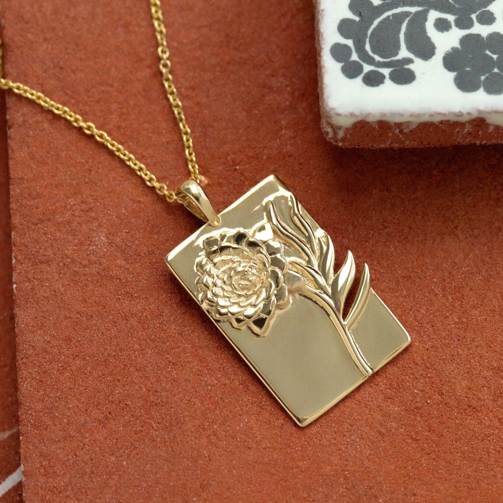 Gold charm pendant with floral design on a red background