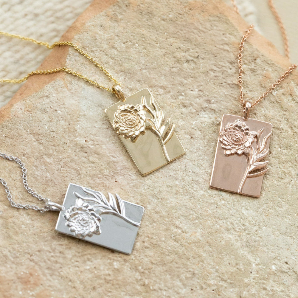Three necklaces with floral pendants on a stone surface