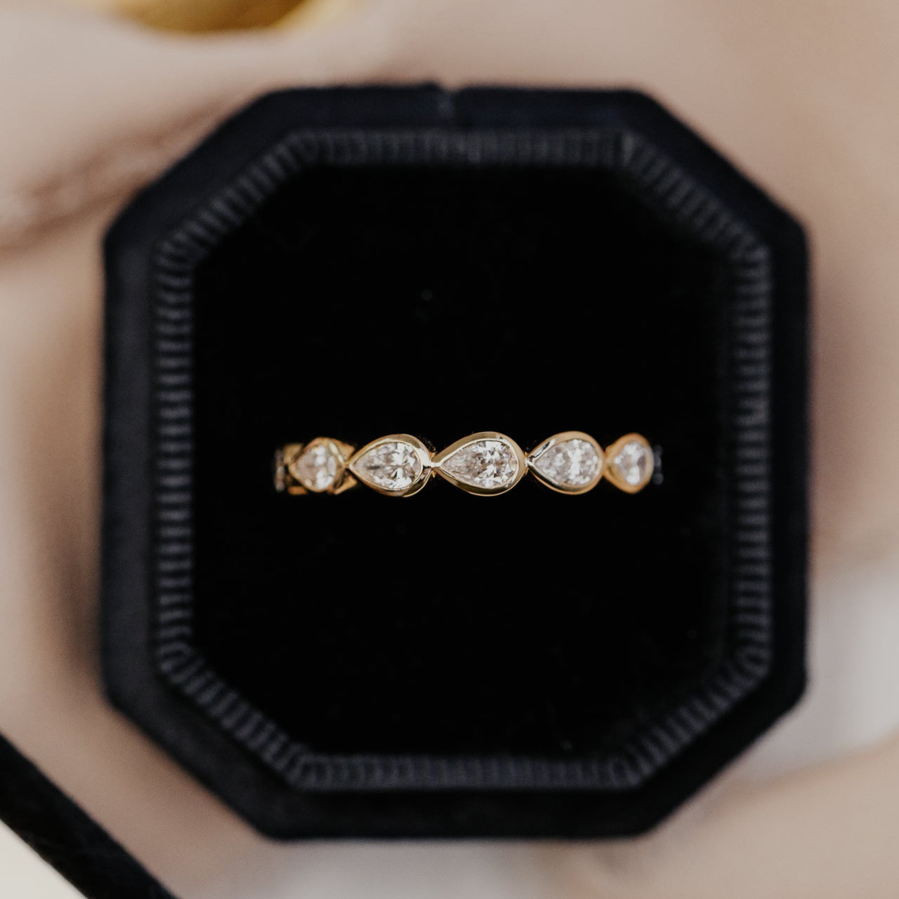 Gold wedding band with pear-shaped diamonds in a black jewelry box