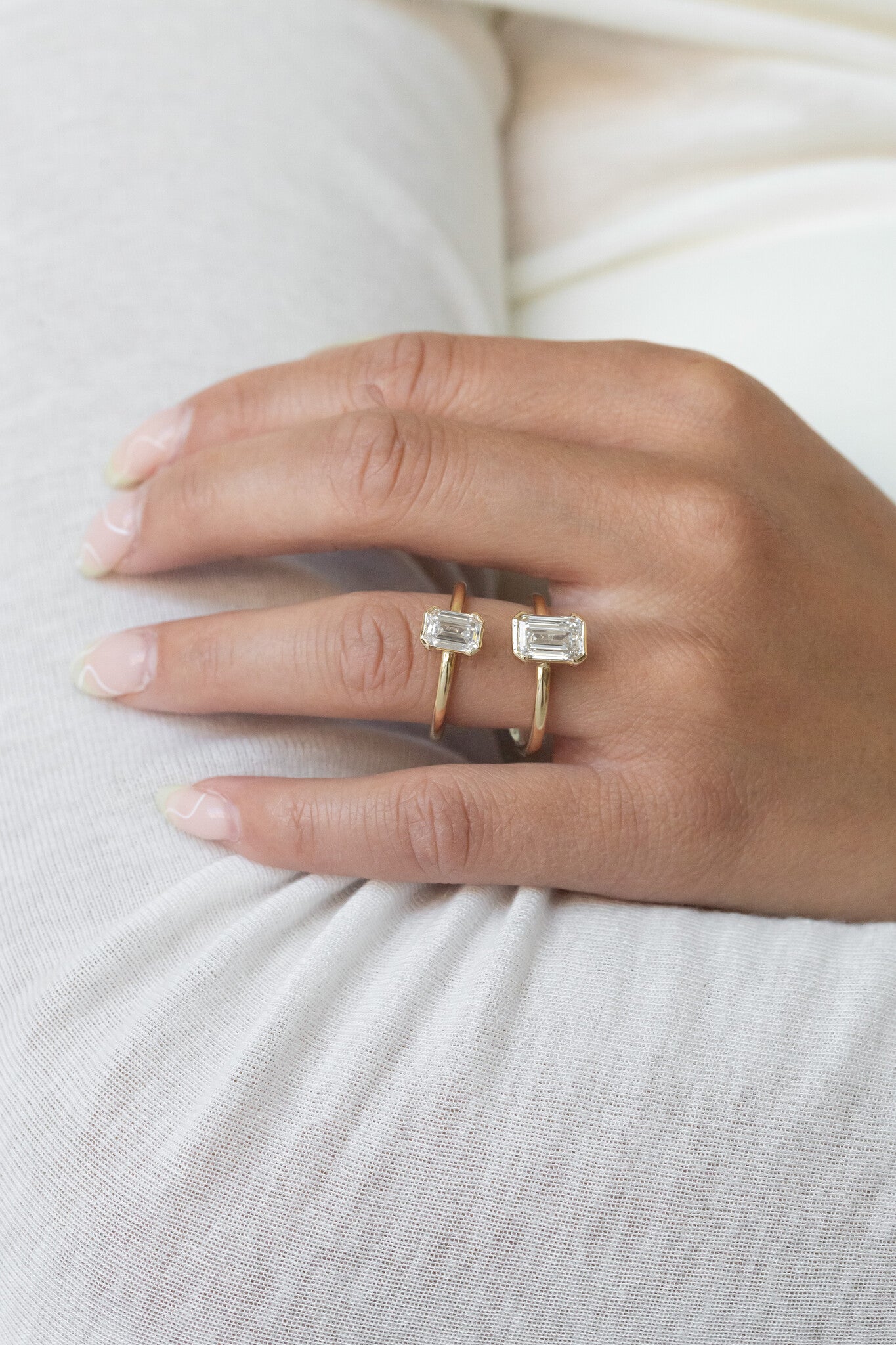 Close up of a hand wearing two Zadie emerald cut diamond engagement rings.